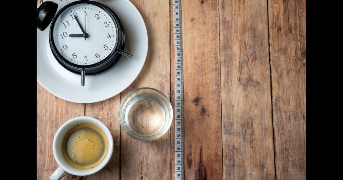 Black coffee and water next to a clock representing intermittent fasting and no-calorie drinks